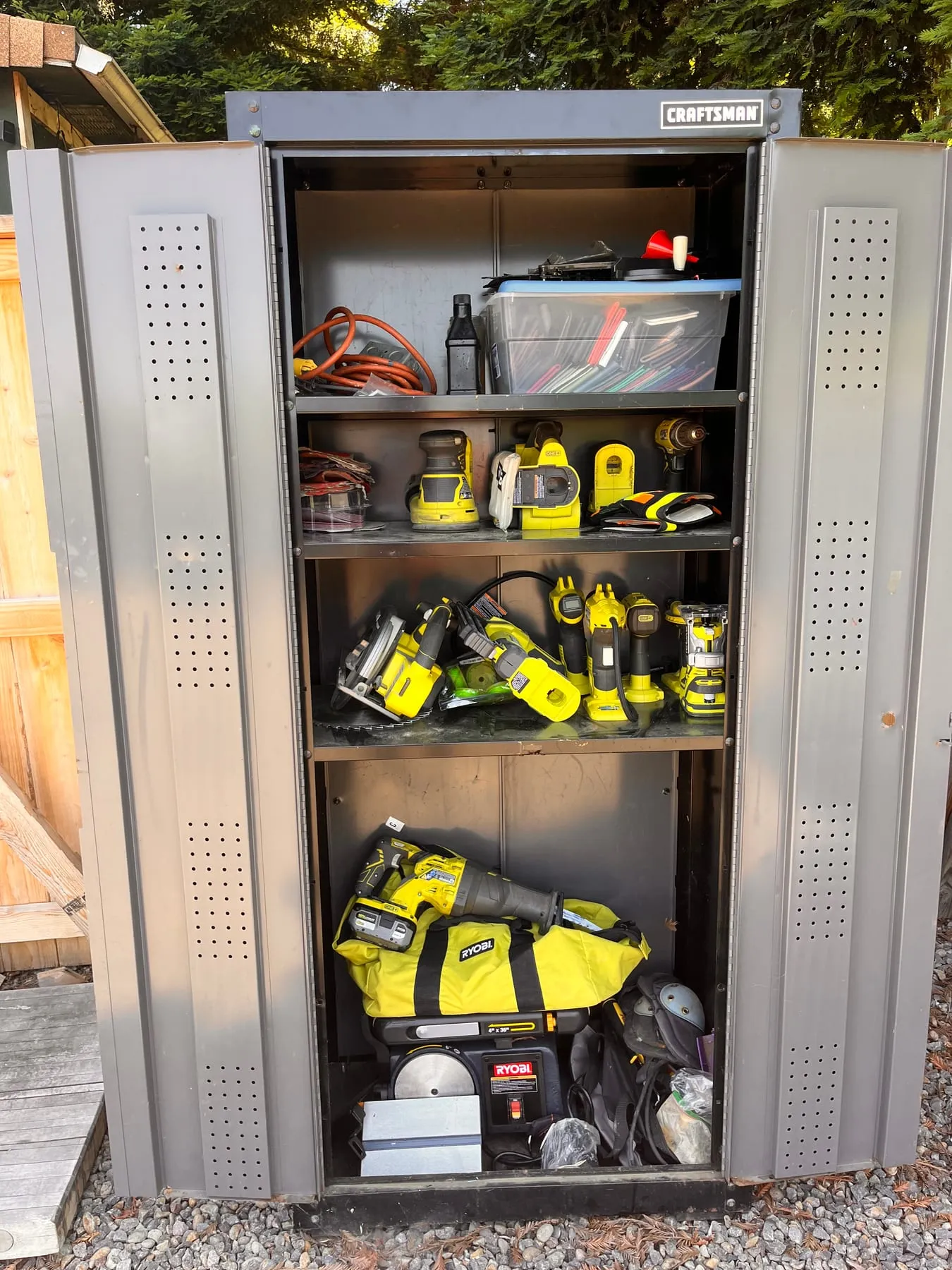 Power tools organized inside a tall outdoor cabinet